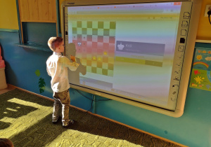 Chłopiec ćwiczy ruchy króla na tablicy interaktywnej
